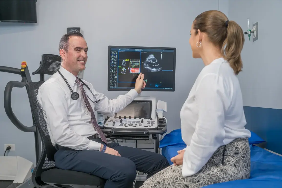 Cardiólogo mostrando resultados de ecocardiograma a paciente en consulta