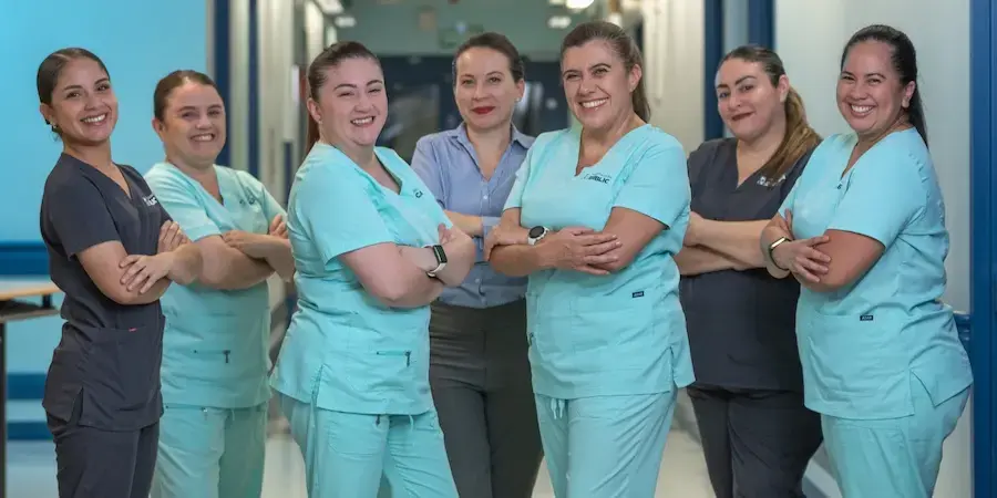 Equipo de enfermería de la Clínica Bíblica posando en pasillo hospitalario con uniformes médicos