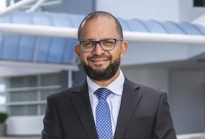 Hombre con traje y corbata posa frente a edificio corporativo moderno
