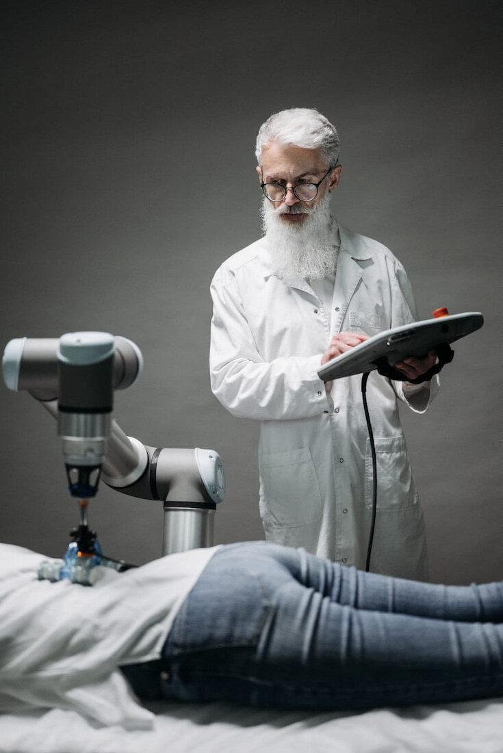 Un profesional médico controla un brazo robótico que examina la espalda de un paciente.