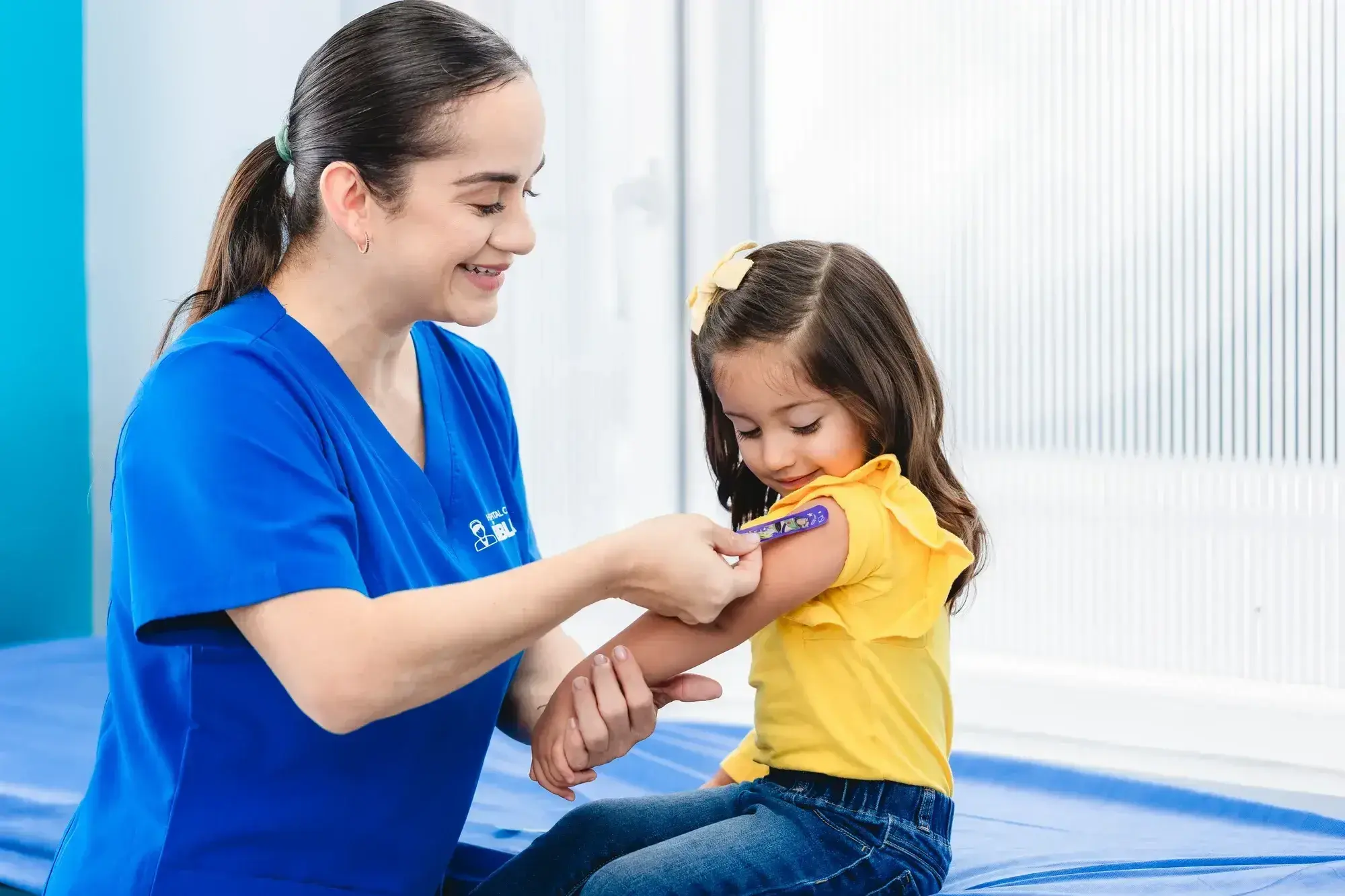 Nurse places band-aid on girl's arm after vaccination at Clínica Bíblica