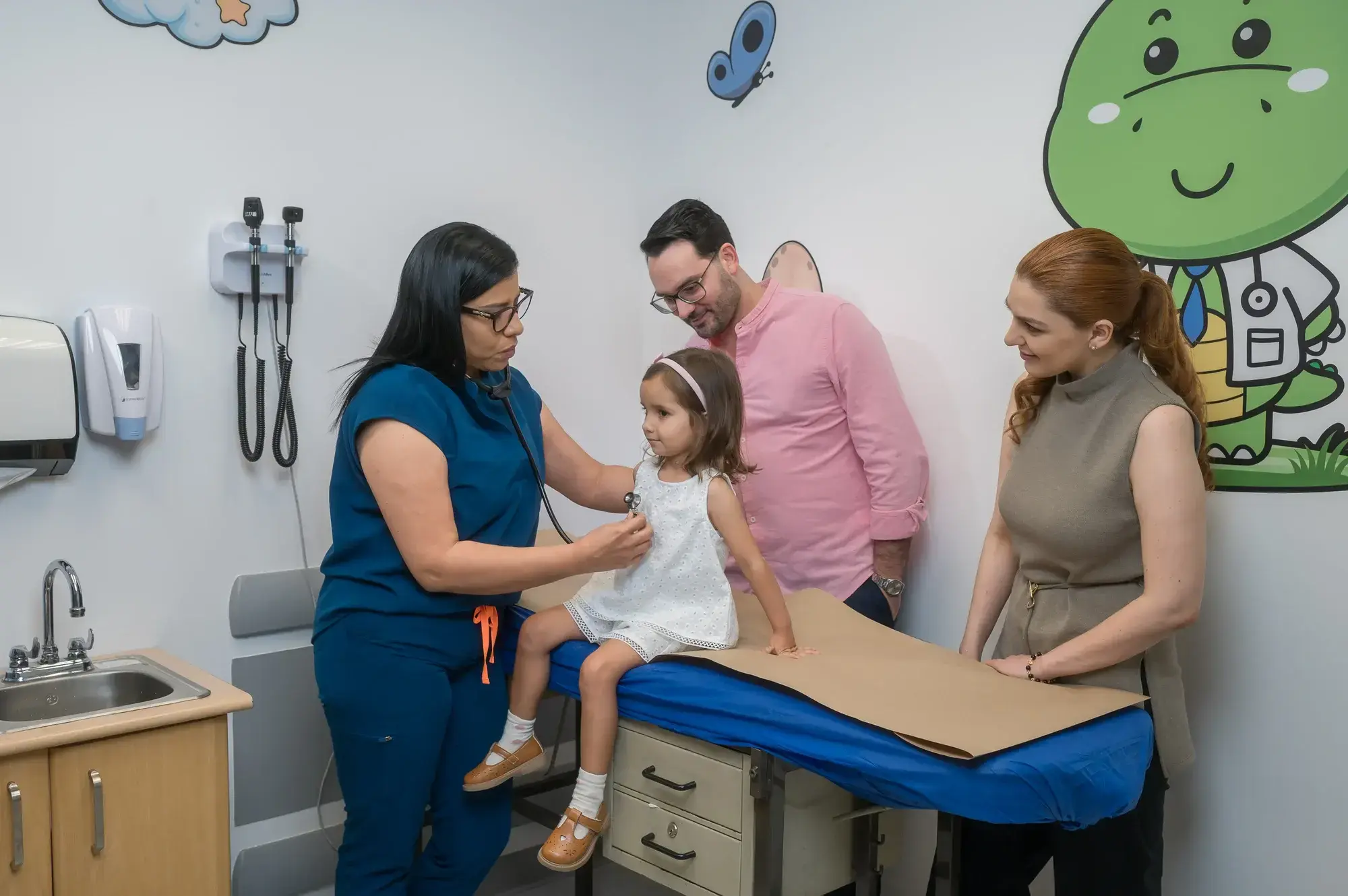 Doctora pediatra revisando con estetoscopio a una niña en consultorio, acompañada de sus padres en Clínica Bíblica.