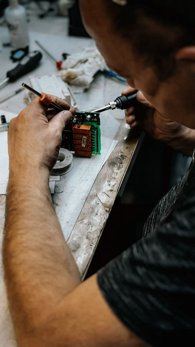 Un técnico utiliza un cautín para soldar componentes detallados en una placa de circuito electrónico en un laboratorio de innovación.